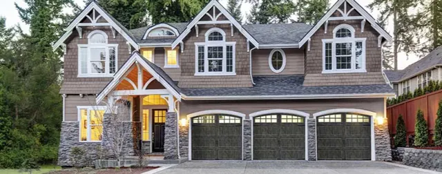 Three dark garage doors on a large stone and timber home