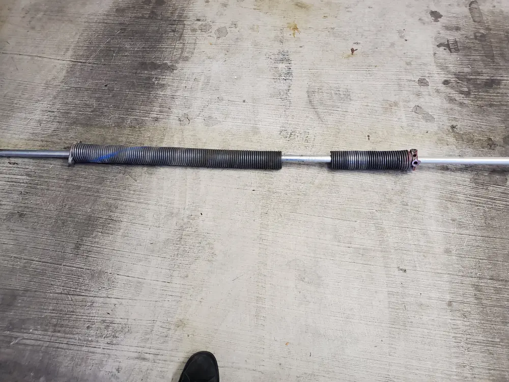 A broken garage door torsion spring on a concrete floor