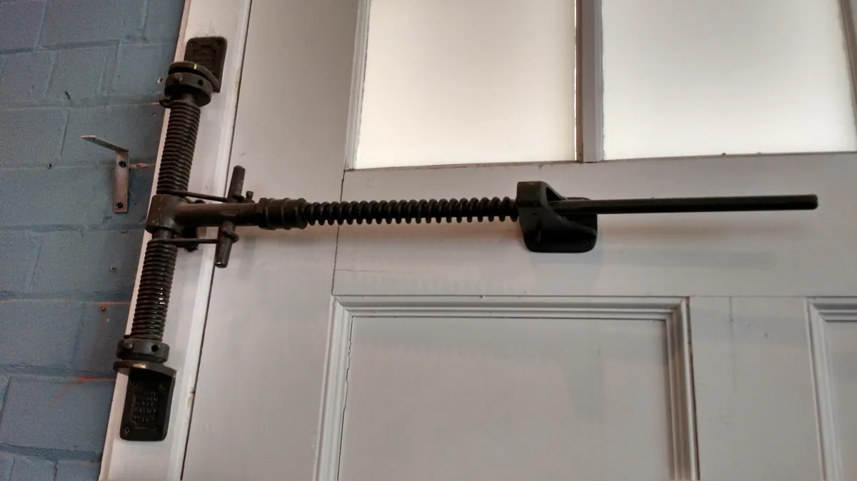 Close-up of garage door spring and hinge hardware on a white door